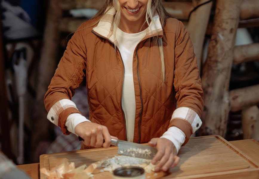 A woman chopping onion in womens fall jacket