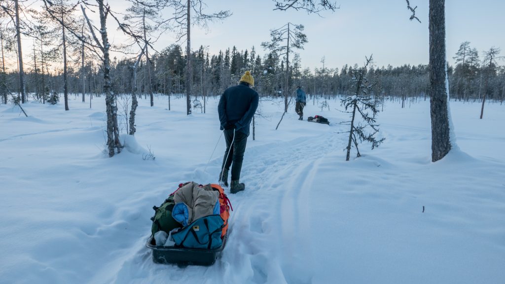 Preparing for Winter in the Backcountry 4 A man in blue coat walking on snow pulling grey wagon with luggages near trees during daytime