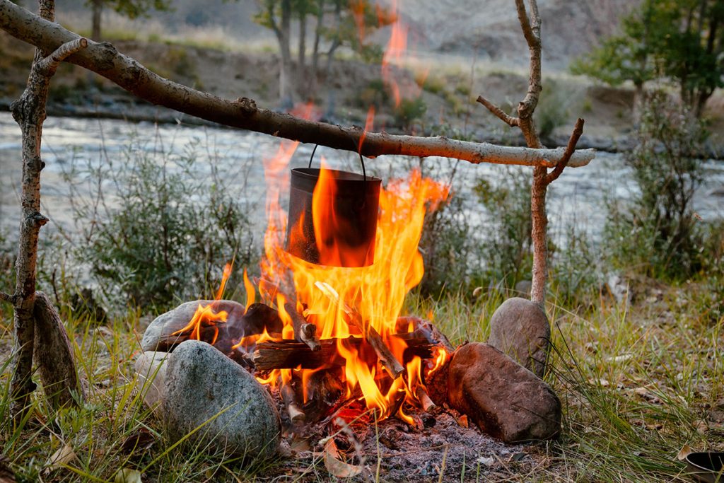 Cooking camp food in cauldron on open fire