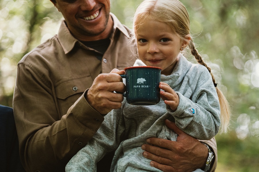 Have We Domesticated the Wild Child - A girl sitting in her father's lap, drinking from a cup.