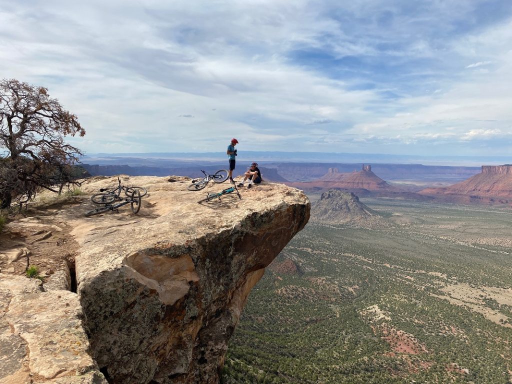 two persons with bicycles on the edge of a cliff