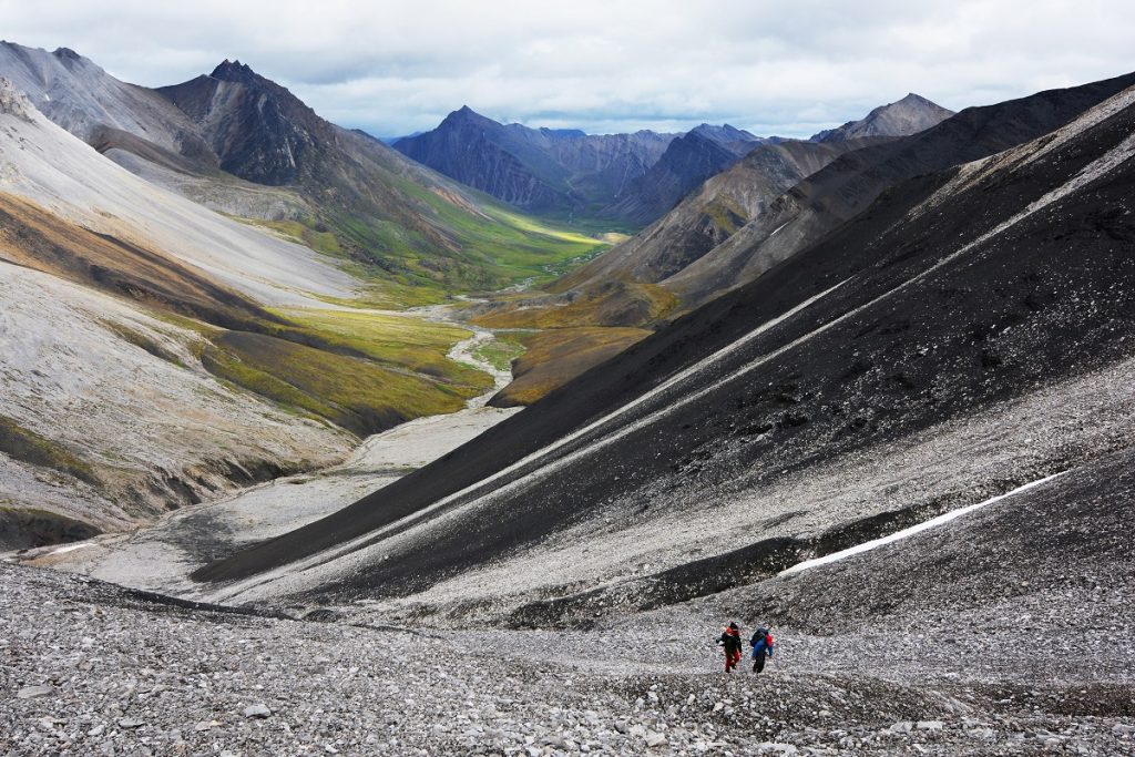 two people walking in front of mountains