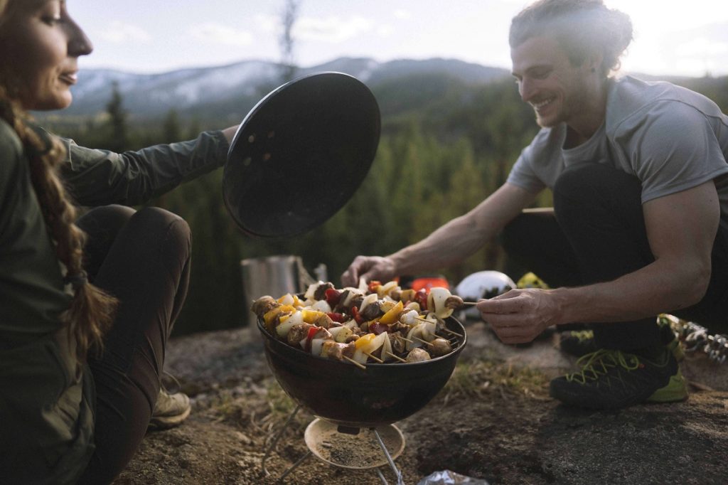 two climbers in KÜHL clothing grilling kebabs in outdoors