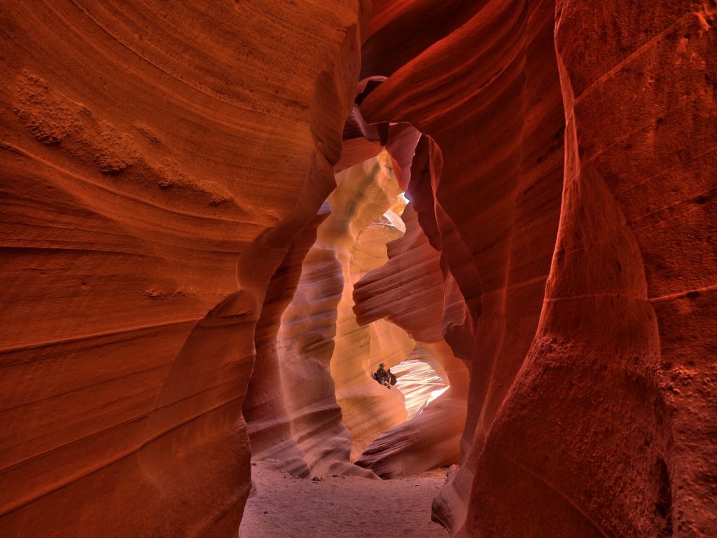 man sitting in the middle of red and brown rock formations