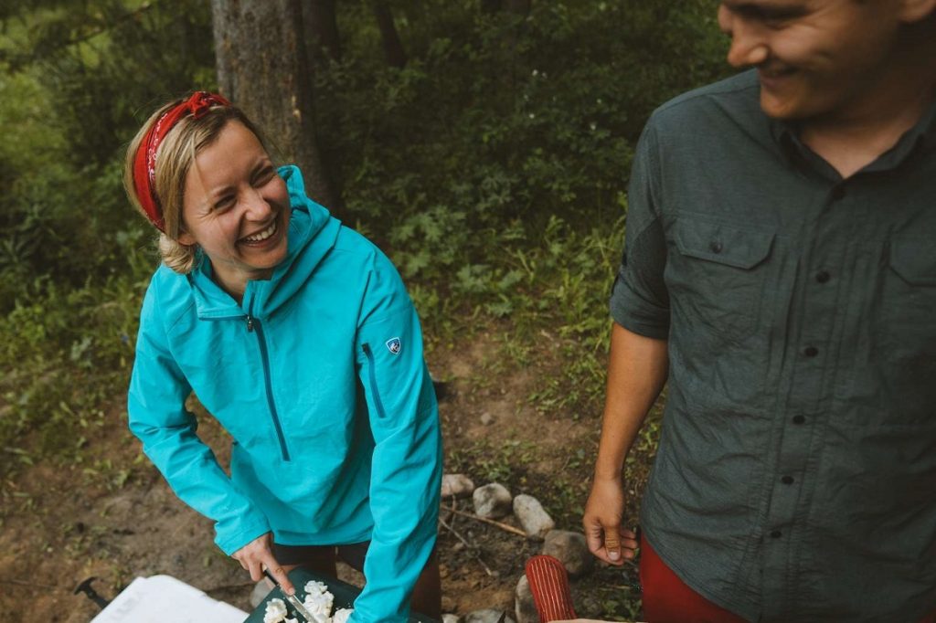 woman in KÜHL jacket cutting vegetables while camping