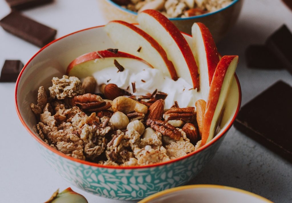 sliced apples and nuts mixed with oats in blue bowl