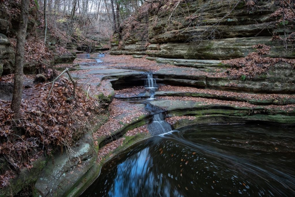 rocky formation with water falling into pond