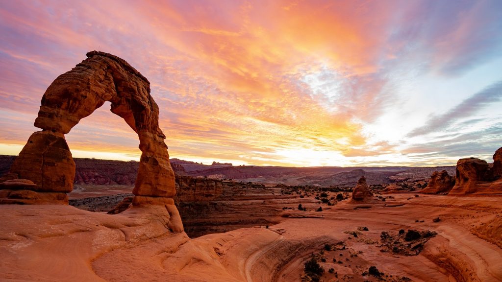 brown rock formation with orange desert and pink sky in background