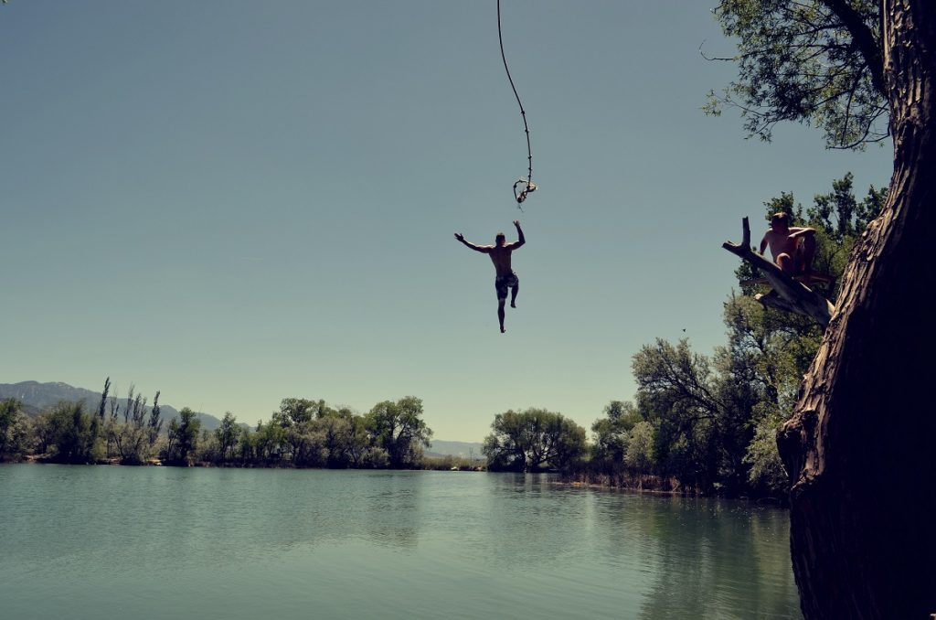 man jumping in body of water