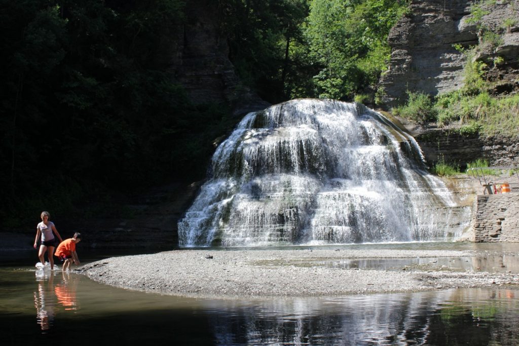 two children standing next to waterfall