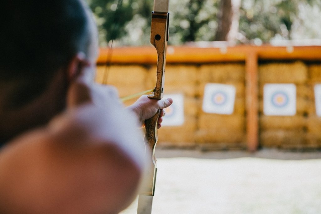 boy aiming bow and arrow on distant target