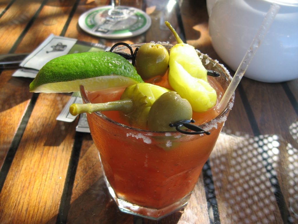 red liquid in glass with pepper and olives on top