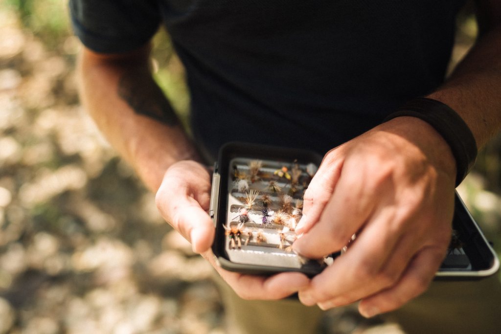 man in KÜHL Engineered Krew holding fly fishing lures