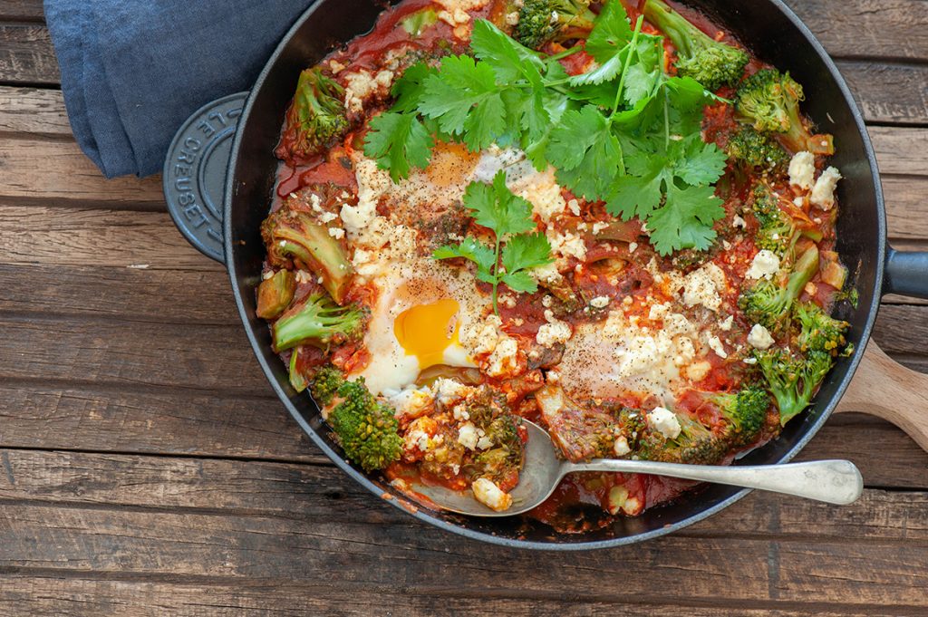 a meal of eggs tomato and parsley in black round pan