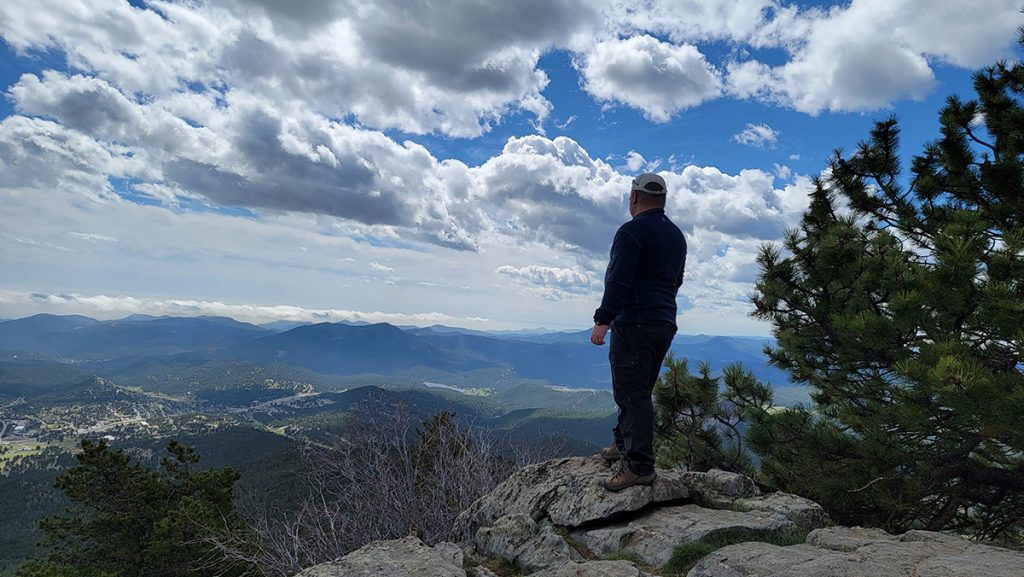 man in KÜHL clothing standing on the overlook during daytime