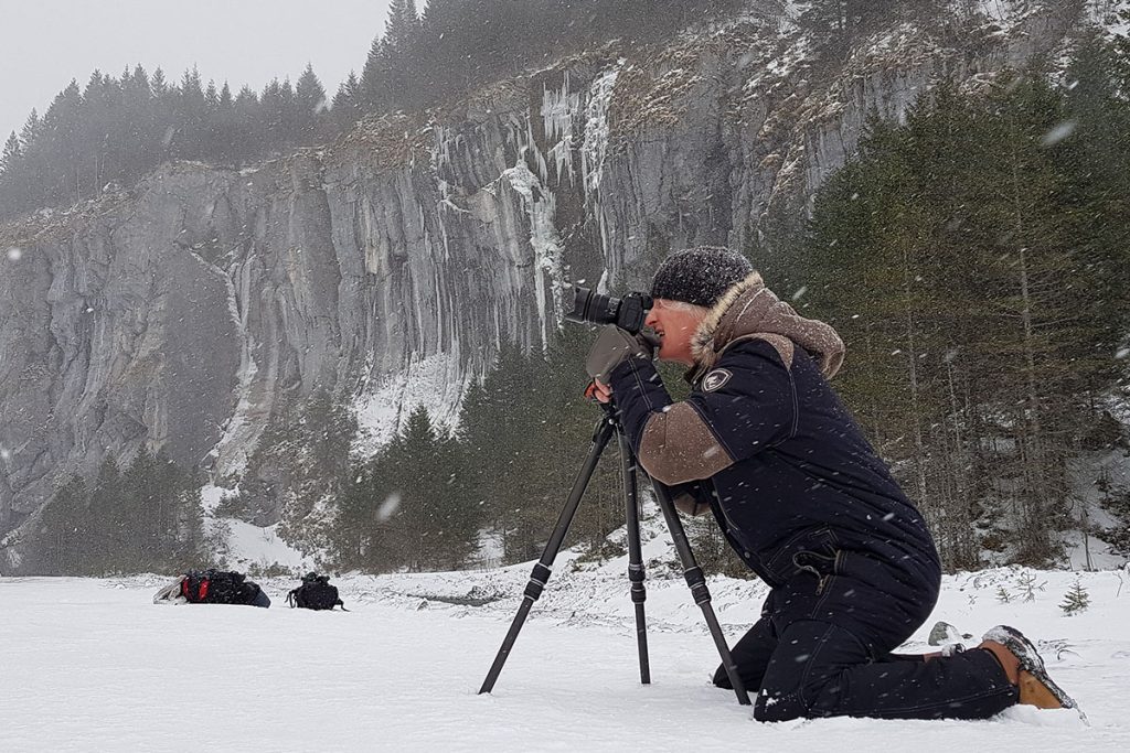 Woman Kneeling In The Snow While Taking A Photo